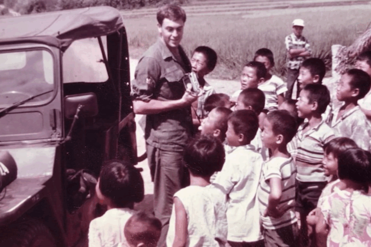 A warm gathering of children joyfully engaging with a smiling adult amid a vibrant outdoor setting.