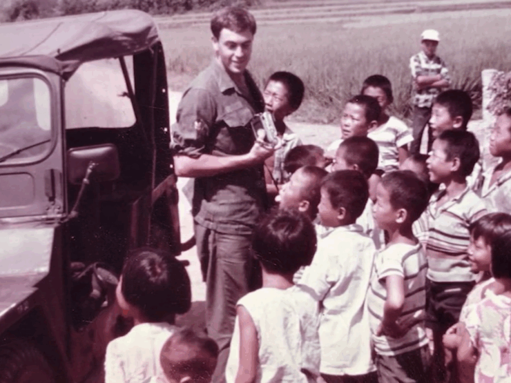 A warm gathering of children joyfully engaging with a smiling adult amid a vibrant outdoor setting.