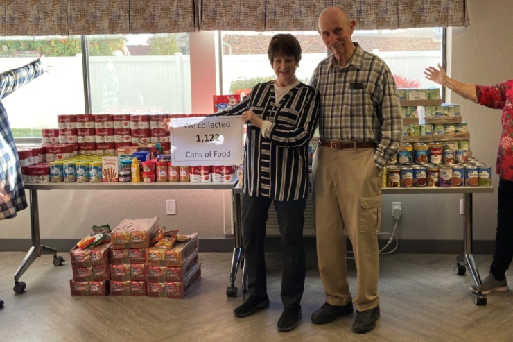 Community members celebrate their successful food drive, showcasing over 1,100 cans collected with joy and teamwork.
