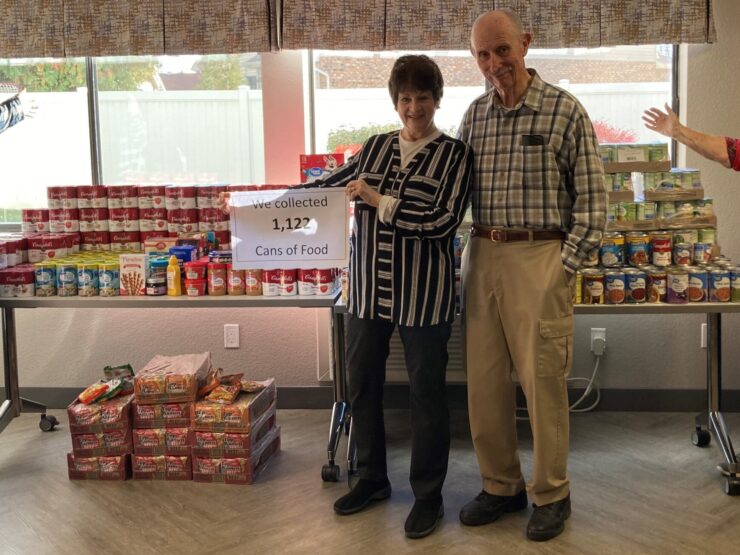 Community members celebrate their successful food drive, showcasing over 1,100 cans collected with joy and teamwork.