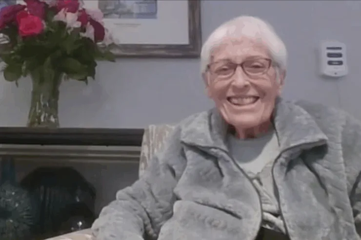 A joyful resident smiles warmly in a welcoming, beautifully decorated environment.