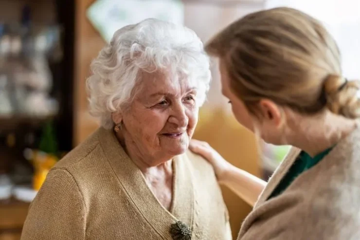 A warm interaction between a caregiver and a resident highlights community and care in a welcoming environment.