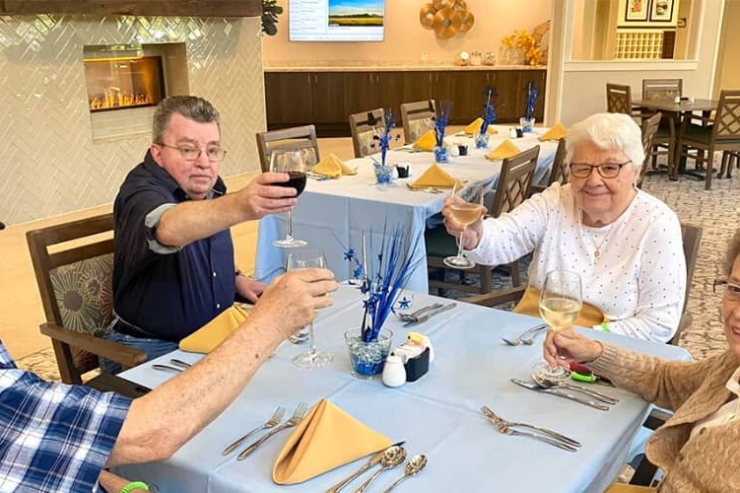 Residents joyfully toast at a beautifully set dining table, embodying community and warmth.