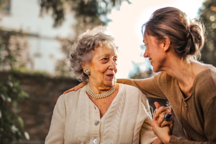 A joyful exchange between a caring staff member and a resident, surrounded by nature, radiates warmth and connection.