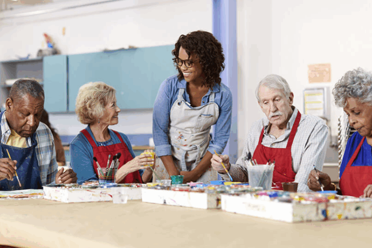 Seniors joyfully engage in a painting class, fostering creativity and community in a warm, inviting space.