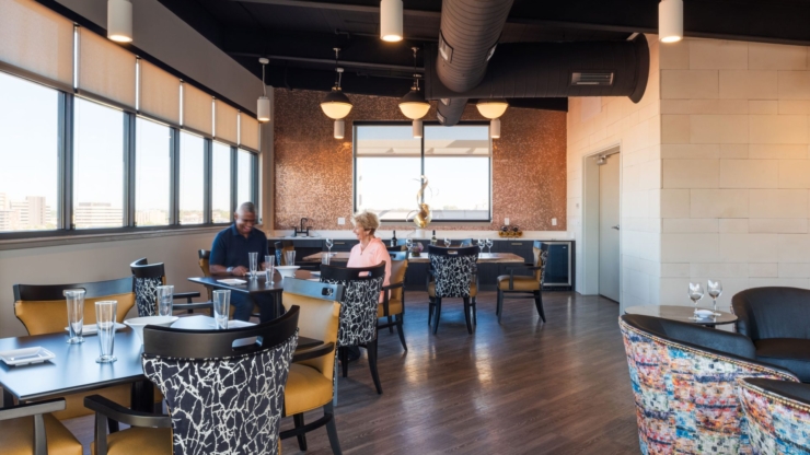 Bright, inviting dining area with engaged residents enjoying each other's company and stunning views.
