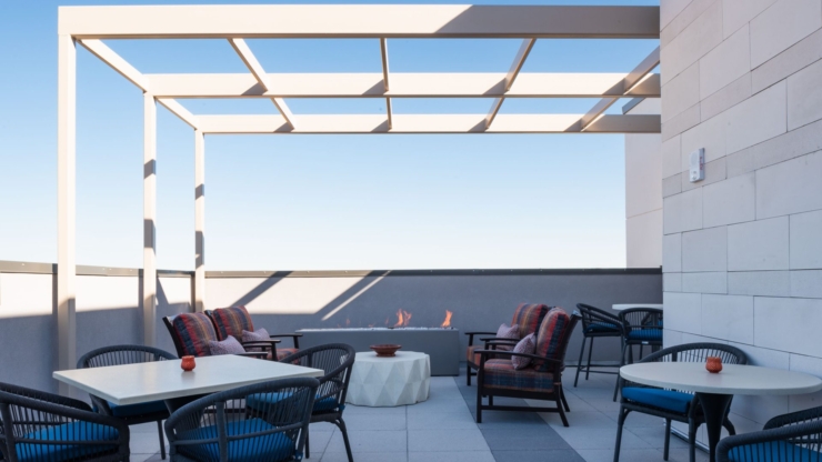 A serene rooftop space with cozy seating, inviting warmth, and a stunning blue sky overhead.
