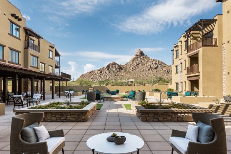 Bright, spacious outdoor seating invites relaxation amidst stunning desert views, fostering a warm community atmosphere.