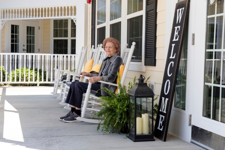 A welcoming porch with a smiling resident enjoying the day, fostering a sense of community and comfort.