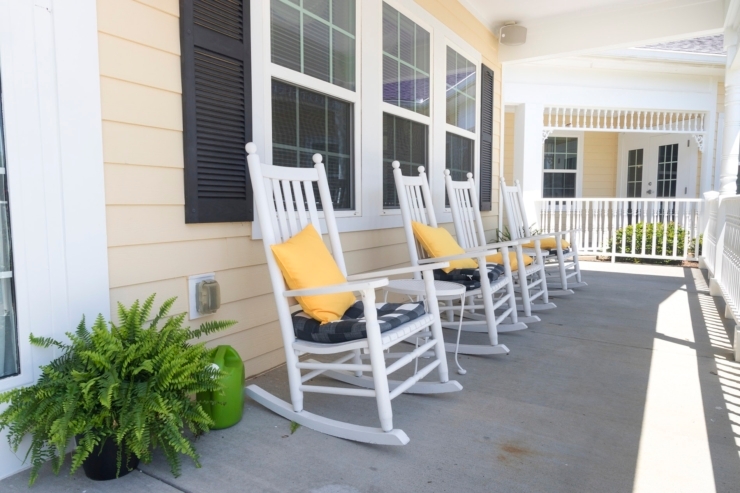 Inviting rocking chairs await on a sunny porch, fostering relaxation and community spirit.