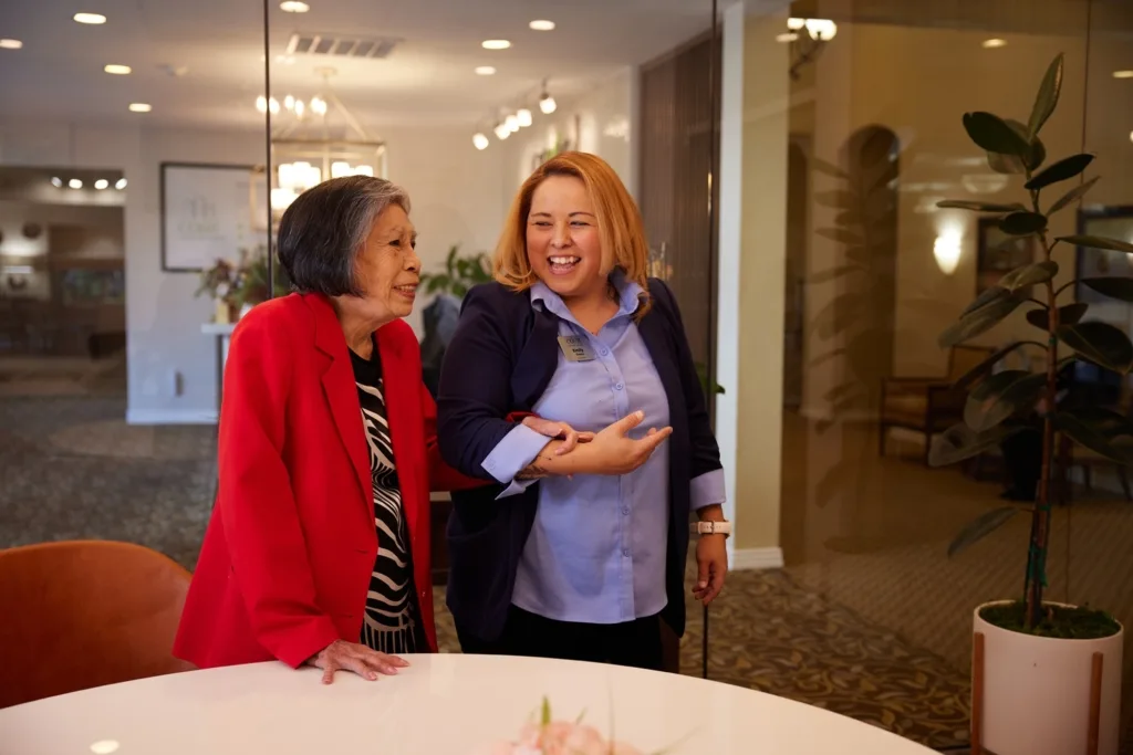 Two women enjoy a lighthearted conversation in a welcoming, bright space, embodying community and warmth.