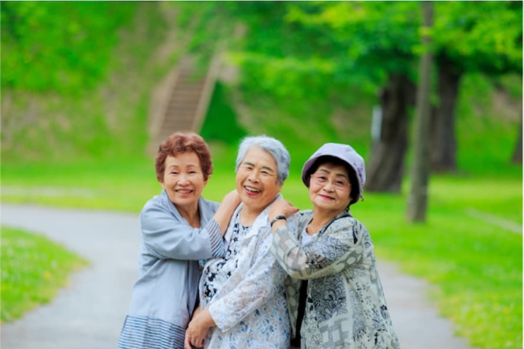 Three joyful friends share laughter in a lush green park, embodying warmth and community spirit.