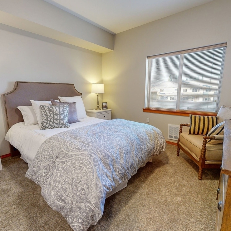 A welcoming bedroom filled with light, featuring comfortable furnishings for relaxation and peace.