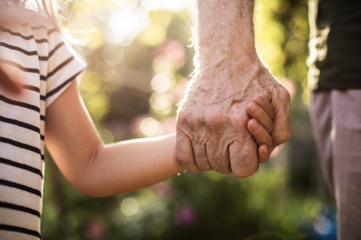 A gentle embrace of hands symbolizes connection and warmth in a serene garden setting.