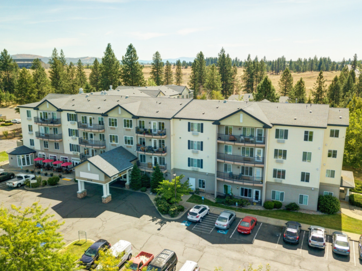 Retirement community nestled among trees with spacious balconies and inviting outdoor seating.