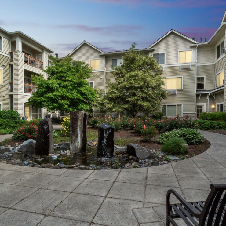 A serene courtyard with vibrant gardens and a soothing water feature invites community and relaxation.