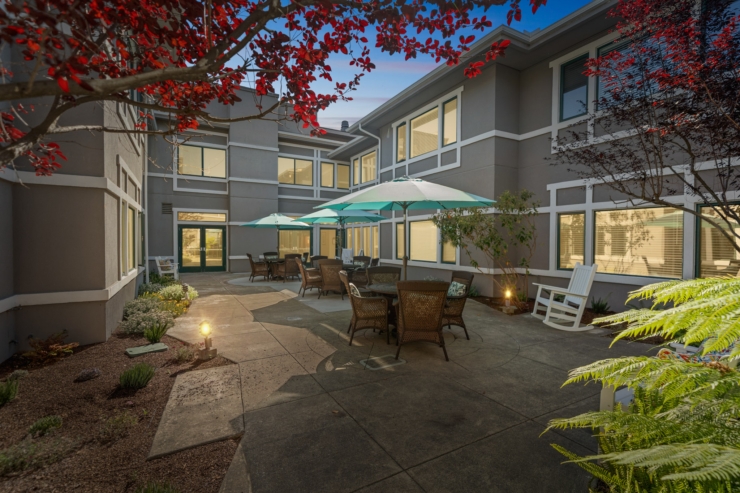 A peaceful courtyard with inviting seating, vibrant greenery, and colorful umbrellas, perfect for community gatherings.