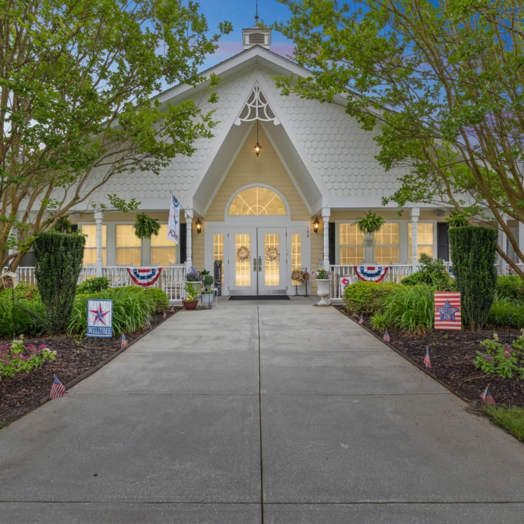 A welcoming entrance with vibrant flowers and flags, inviting residents into a warm community atmosphere.