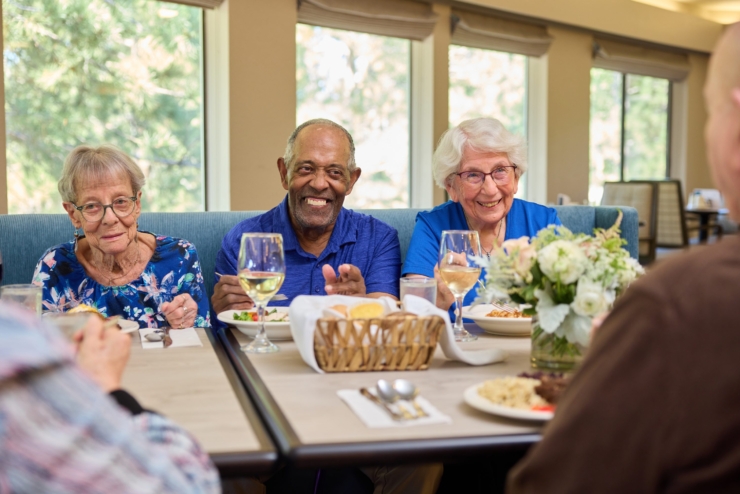 A joyful gathering of friends enjoying a meal, surrounded by bright natural light and warmth.