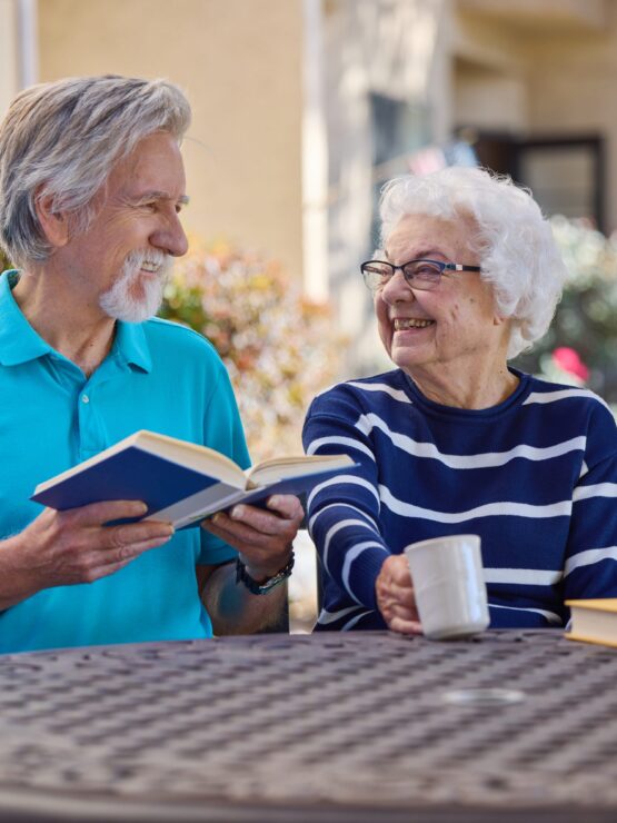 Senior man and women sit together reading.