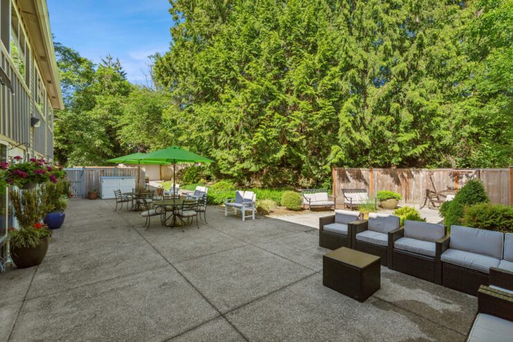 A serene outdoor space featuring comfortable seating, vibrant greenery, and inviting tables for gatherings.