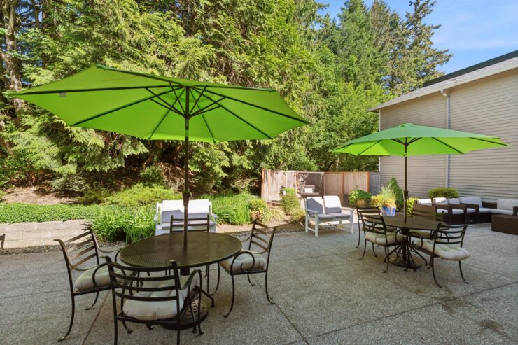 A serene outdoor space with inviting seating under vibrant green umbrellas, surrounded by lush greenery.