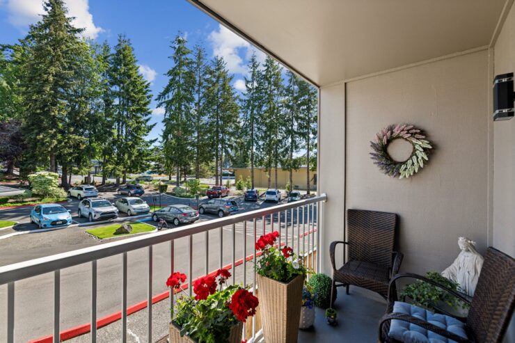 A serene balcony adorned with vibrant flowers offers a welcoming view of lush trees and friendly neighbors.