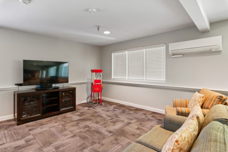 A welcoming lounge with comfortable seating, a TV, and a vintage popcorn machine, perfect for community gatherings.