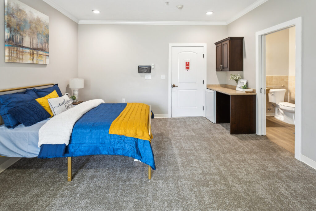 A cozy, inviting room with warm colors, featuring a comfortable bed and thoughtful amenities for residents.