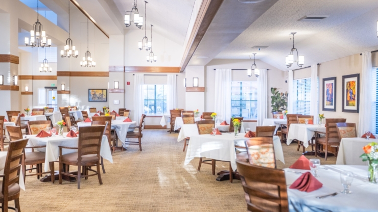 Bright and inviting dining area, featuring elegant tables adorned with flowers, fostering community warmth.