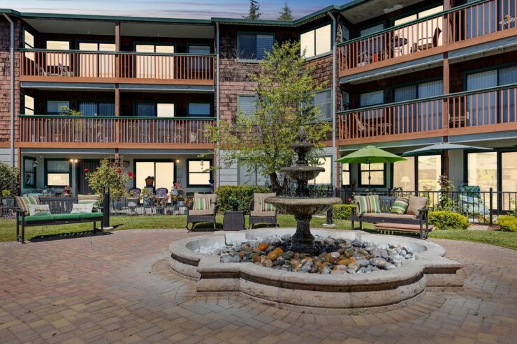 A welcoming courtyard features a charming fountain, inviting seating, and vibrant greenery, perfect for community gatherings.