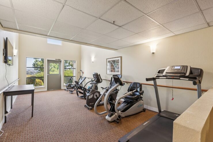 Bright and inviting fitness area, featuring modern equipment and large windows, fostering community wellness.
