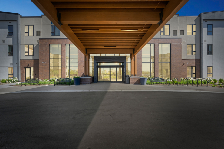 A welcoming entrance with beautiful landscaping, inviting benches, and large windows radiates warmth and community.