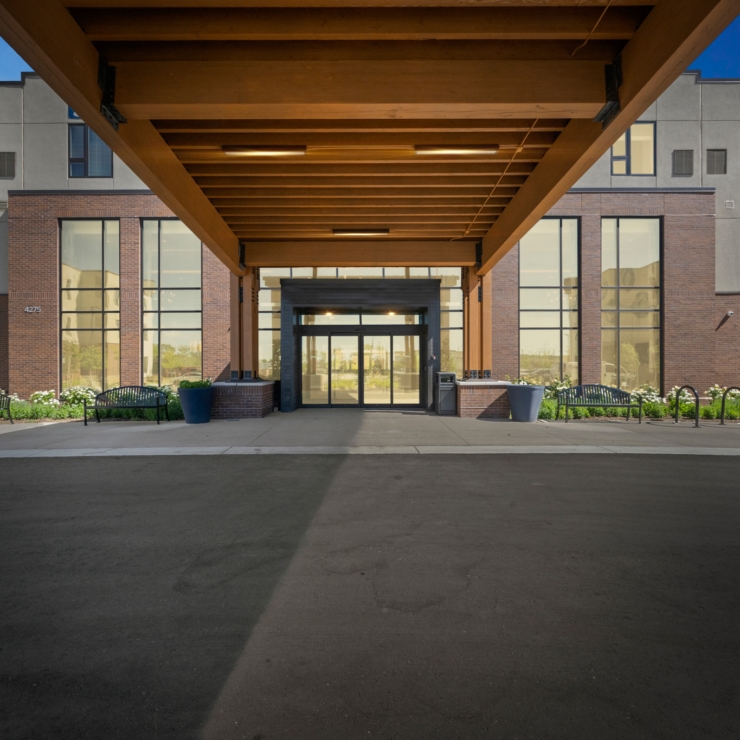A welcoming entrance with beautiful landscaping, inviting benches, and large windows radiates warmth and community.