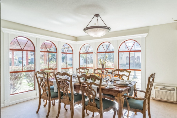 Bright dining area with elegant furniture, inviting light through arched windows, fostering community.