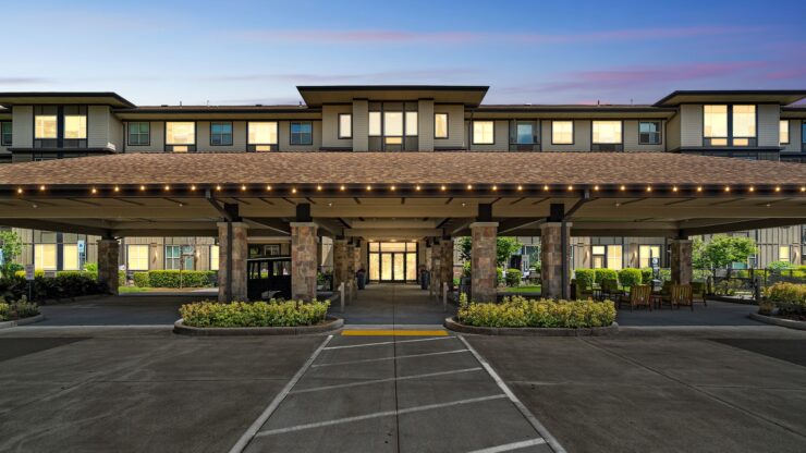 Welcoming entrance with beautifully lit awning, surrounded by lush greenery and inviting seating areas.