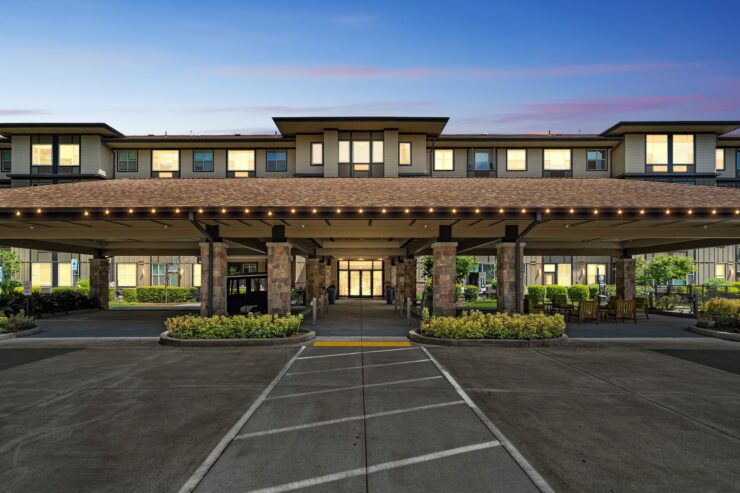 Welcoming entrance with beautifully lit awning, surrounded by lush greenery and inviting seating areas.