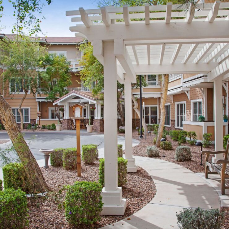 Outdoor seating area with shaded walkway and well-maintained landscaping in a welcoming community setting.