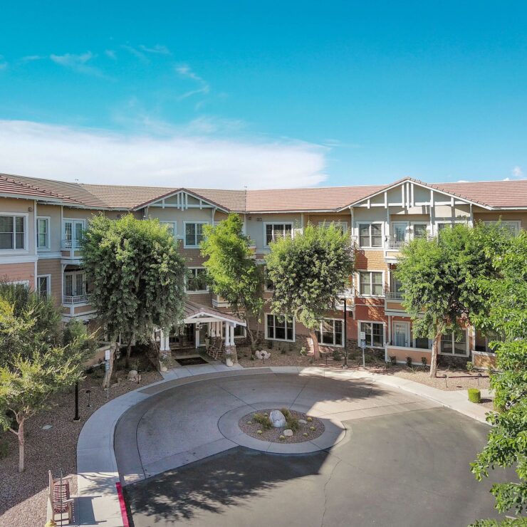 A bright, welcoming retirement community with shaded walkways and lush greenery.