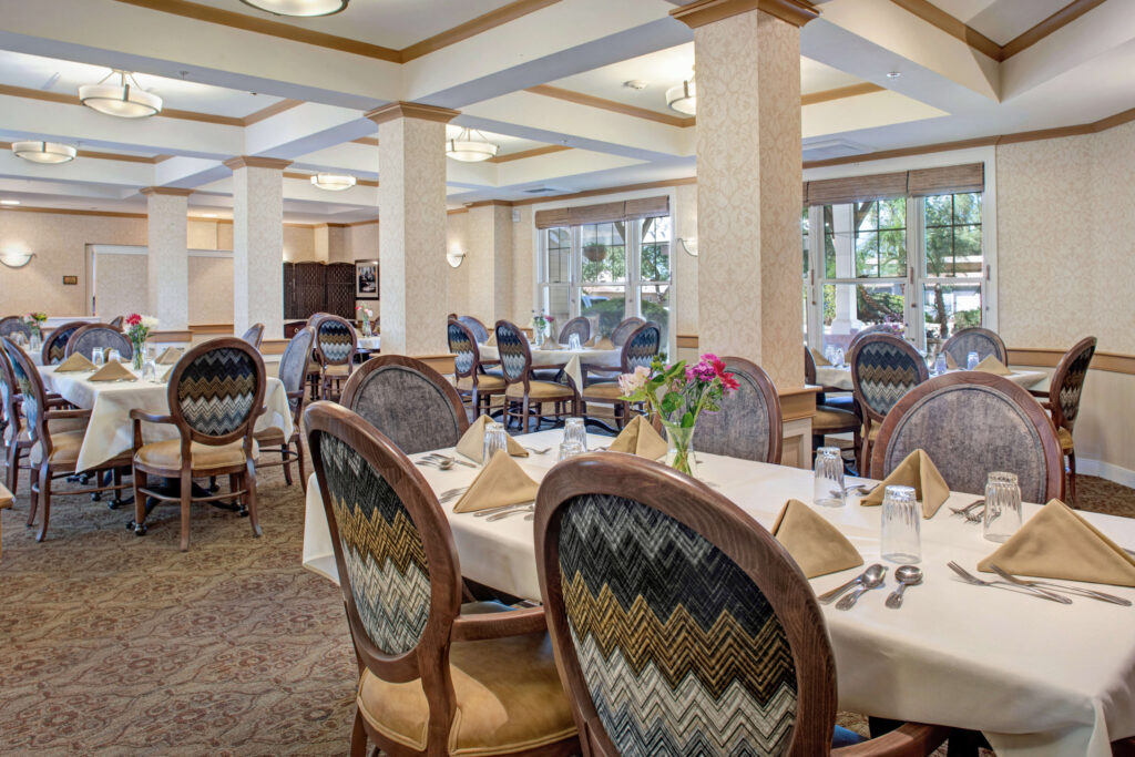 Bright, inviting dining room with elegant seating and fresh flowers, fostering community and comfort.