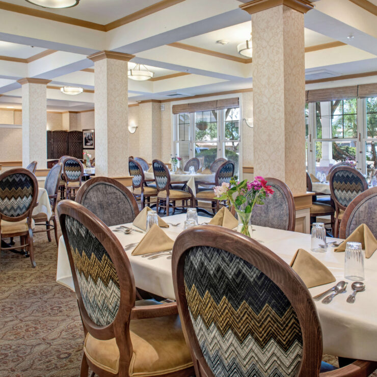 Bright, inviting dining room with elegant seating and fresh flowers, fostering community and comfort.