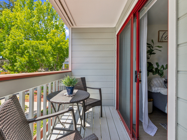 A sunlit balcony with inviting seating, surrounded by lush greenery, fosters a sense of community and comfort.