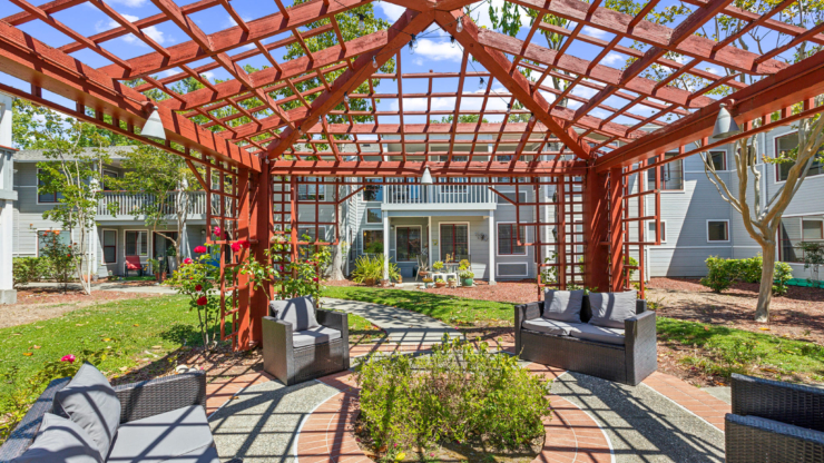 A charming garden setting with comfortable seating invites community interactions under a trellis.