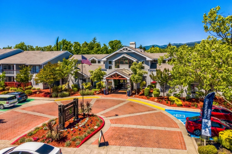 A welcoming community entrance, adorned with vibrant gardens and warm sunlight, inviting all.