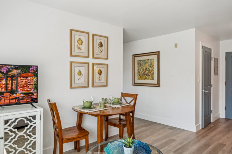 A bright, inviting dining area features a charming table set for two, surrounded by artful décor, fostering community and warmth.