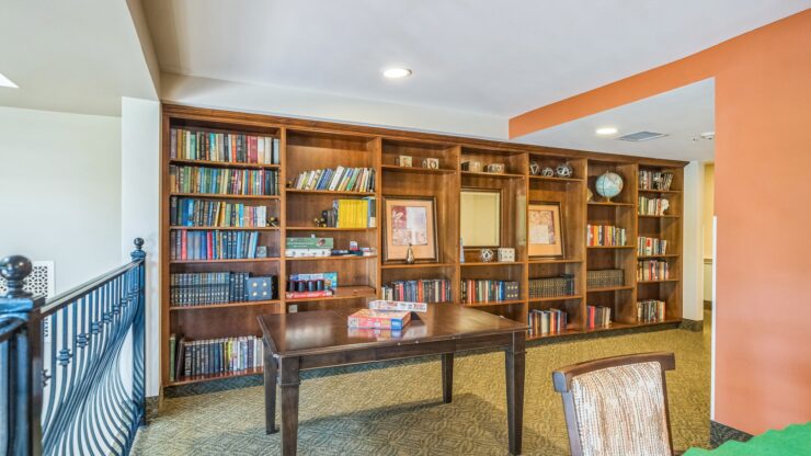 A welcoming reading area with a rich bookshelf, inviting table, and warm colors, perfect for community gatherings.