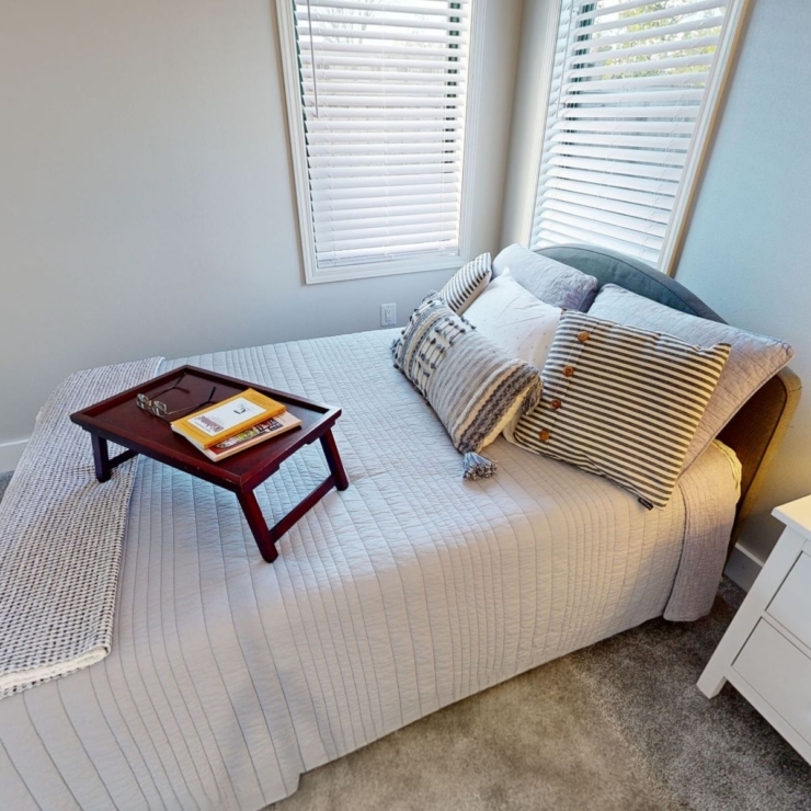A bright, inviting bedroom featuring a neatly made bed, warm lighting, and cheerful decor, promoting comfort.
