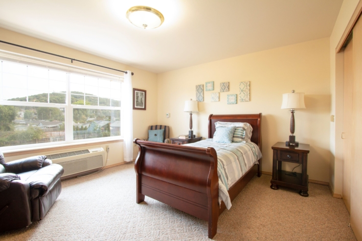 A bright, inviting room with a cozy bed, comfortable seating, and scenic views, perfect for relaxation.