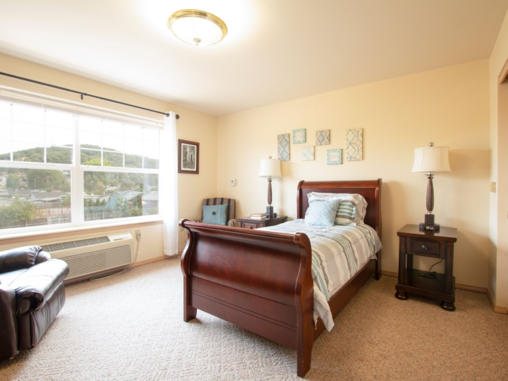A bright, inviting room with a cozy bed, comfortable seating, and scenic views, perfect for relaxation.