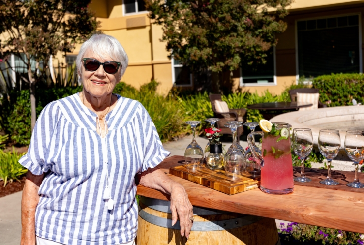 A cheerful resident enjoys a sunny day by the refreshing beverage station, embodying community spirit.